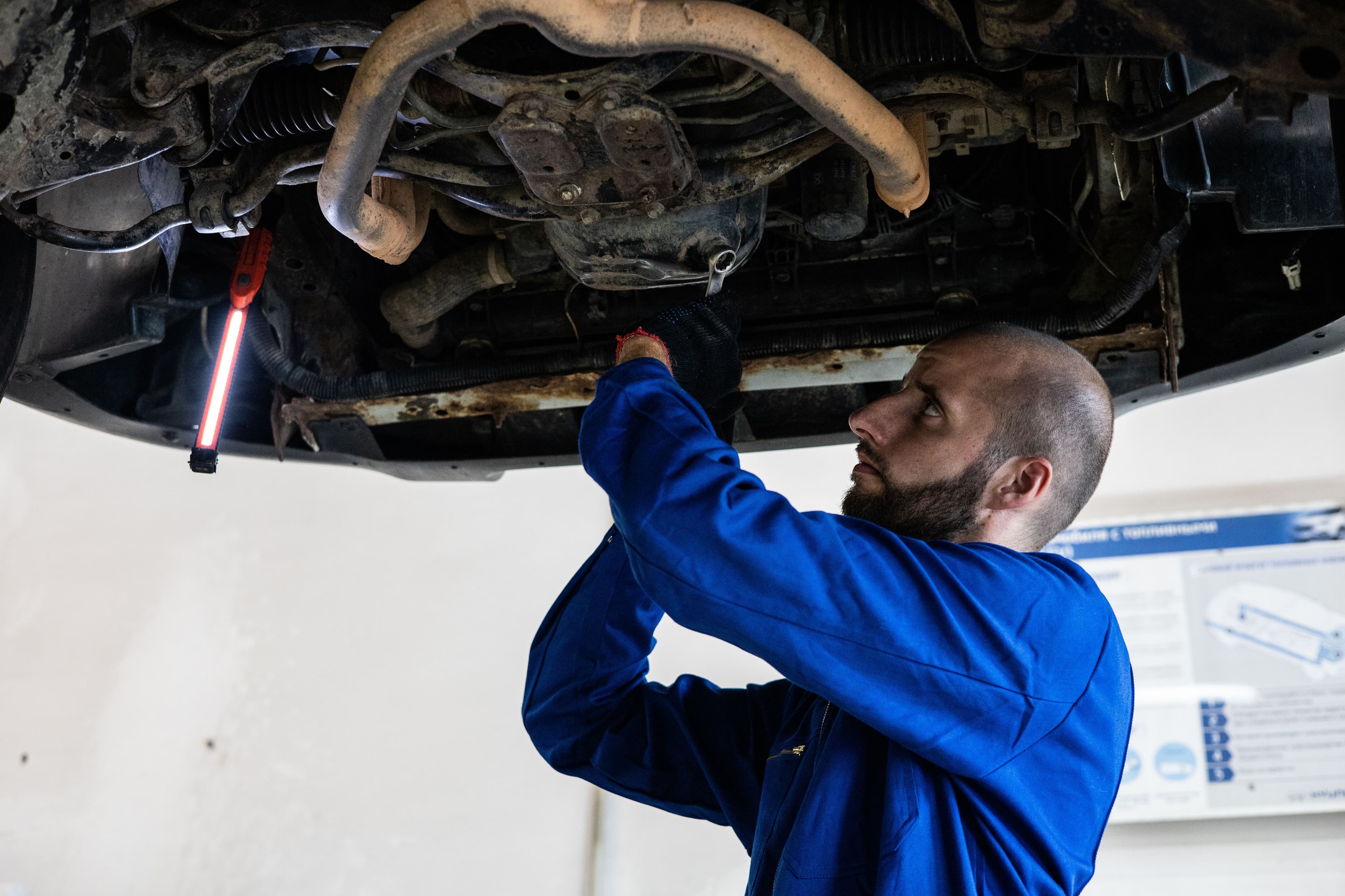 Mechanic inspecting the underside of a raised vehicle during transfer case diagnosis