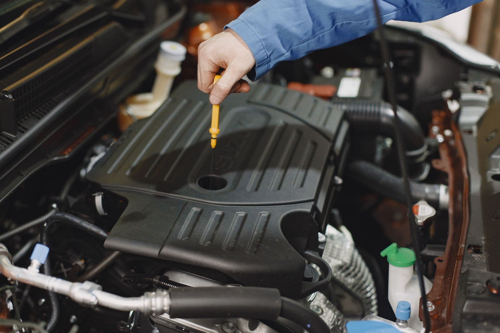 Mechanic inspecting engine oil on a dipstick during coolant contamination diagnosis