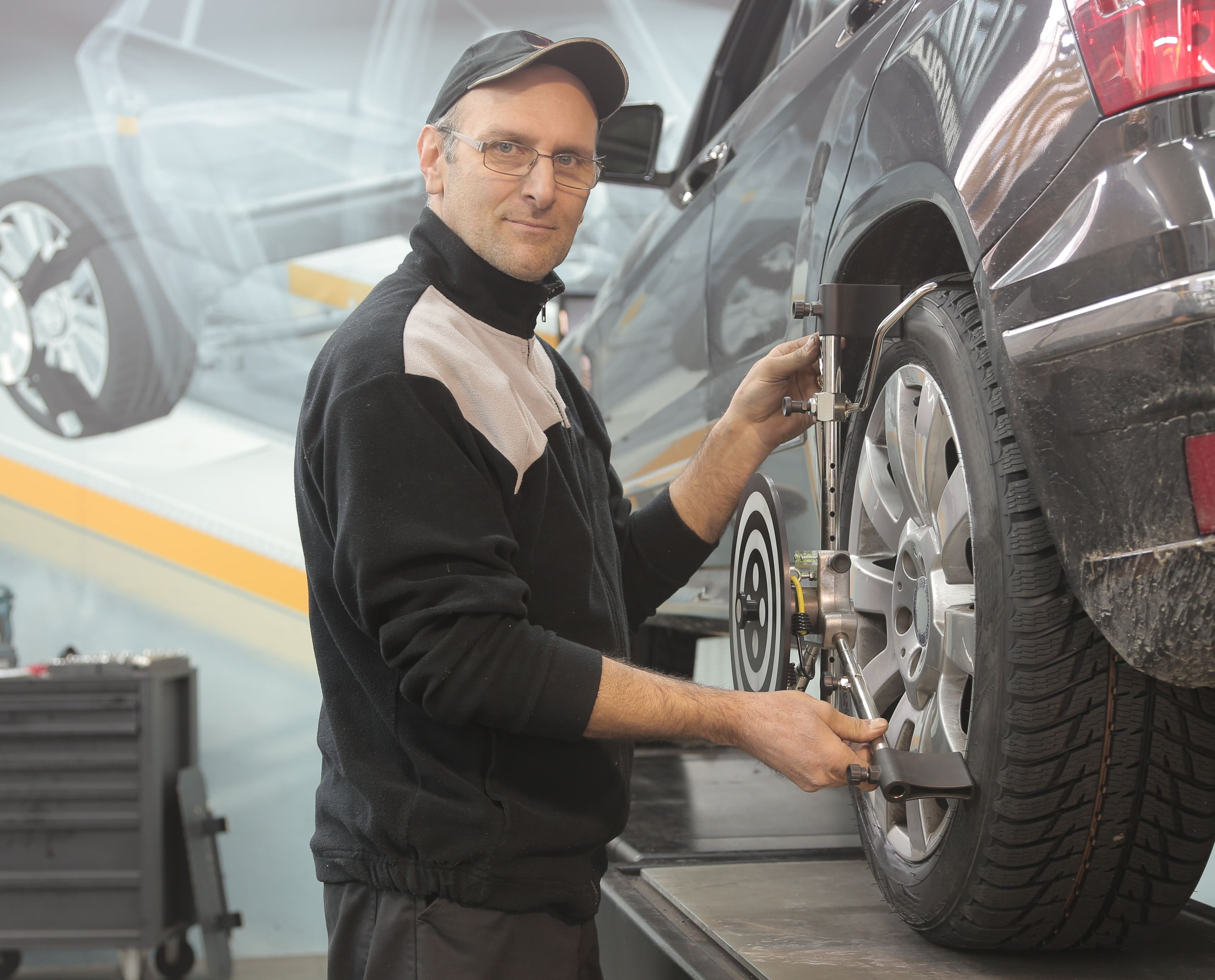 Mechanic performing a wheel alignment while diagnosing uneven rear tire wear