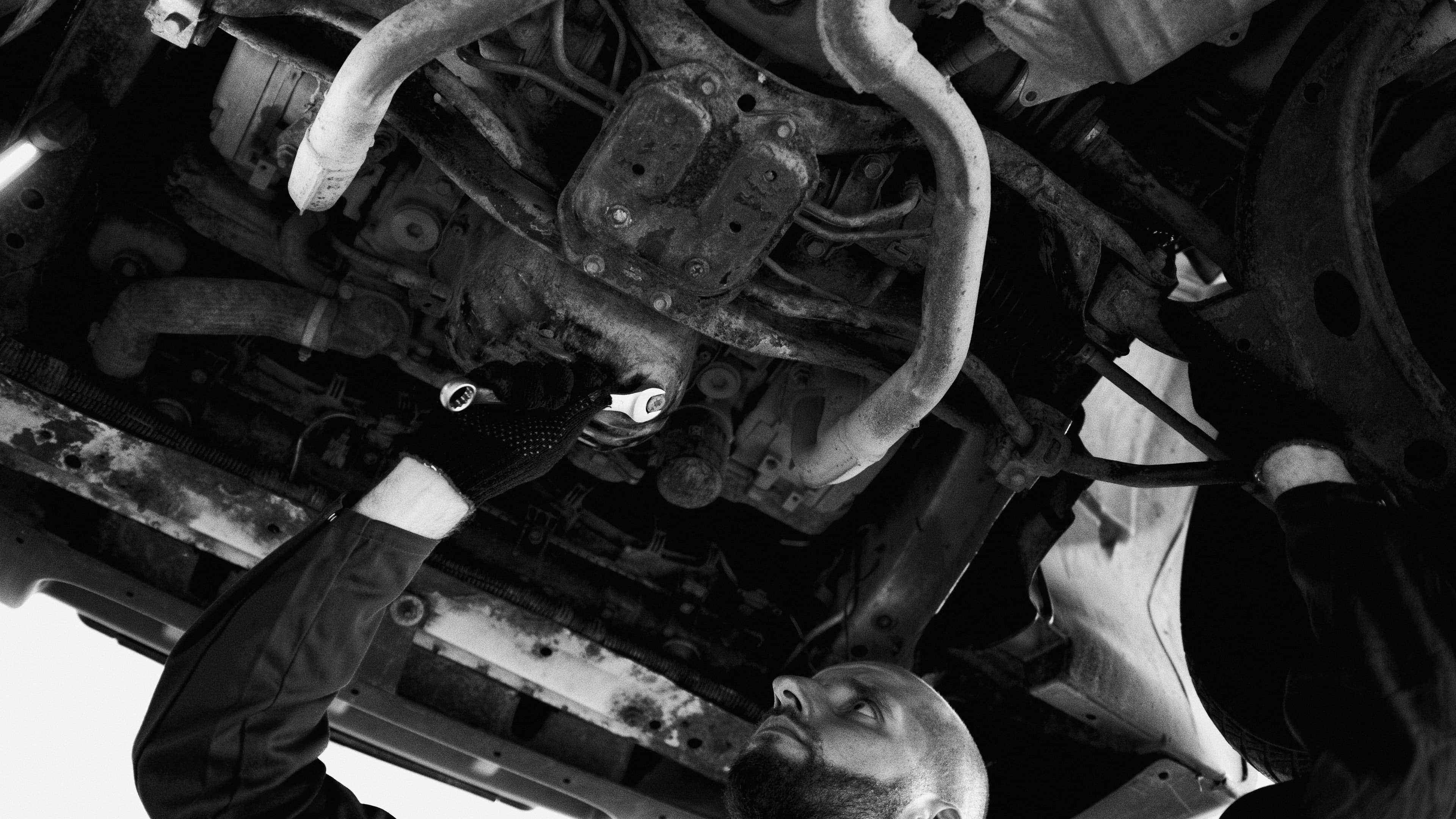 Mechanic inspecting the underside and driveline of a vehicle on a lift