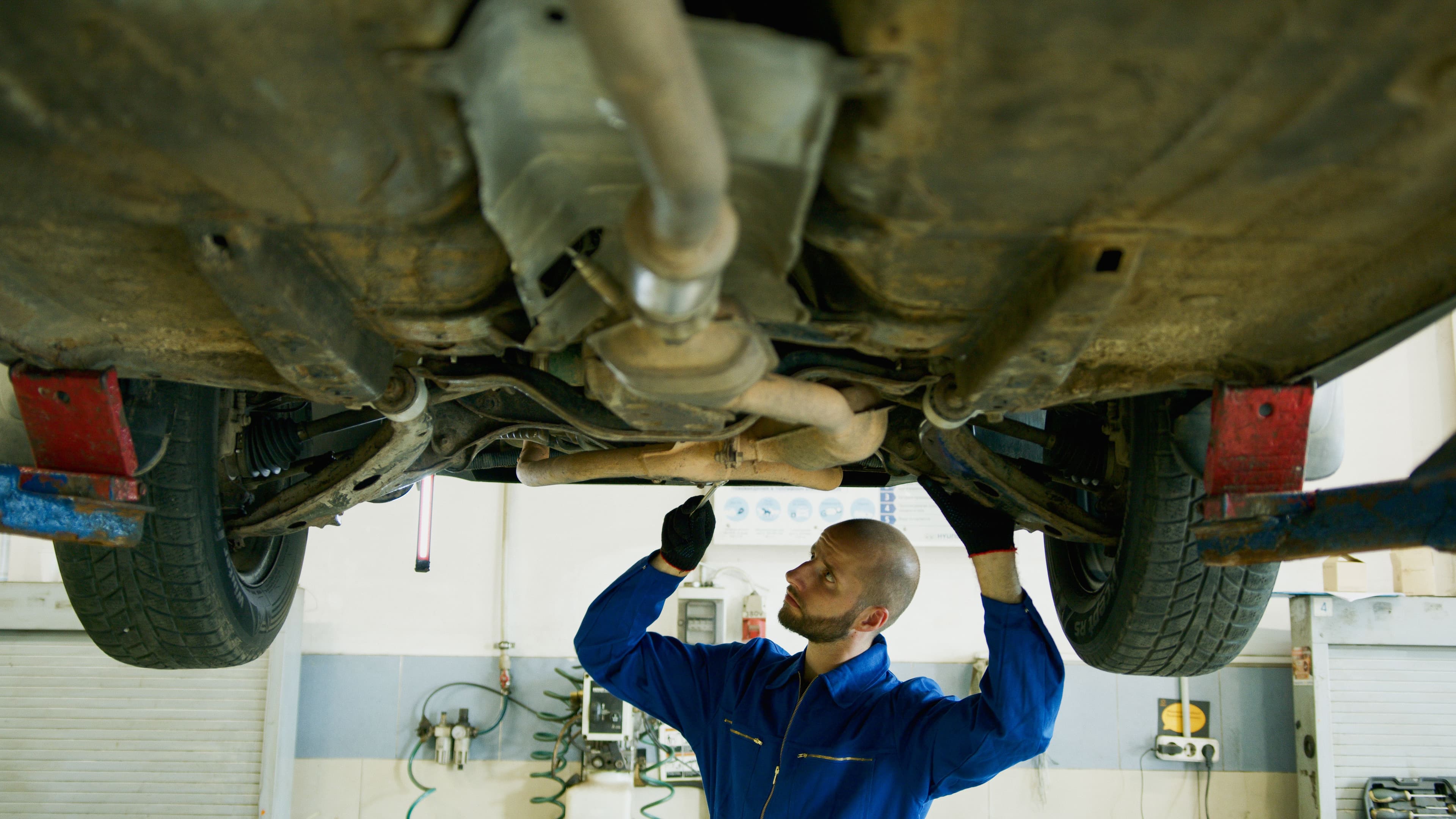 Mechanic inspecting the underside of a vehicle before transmission service