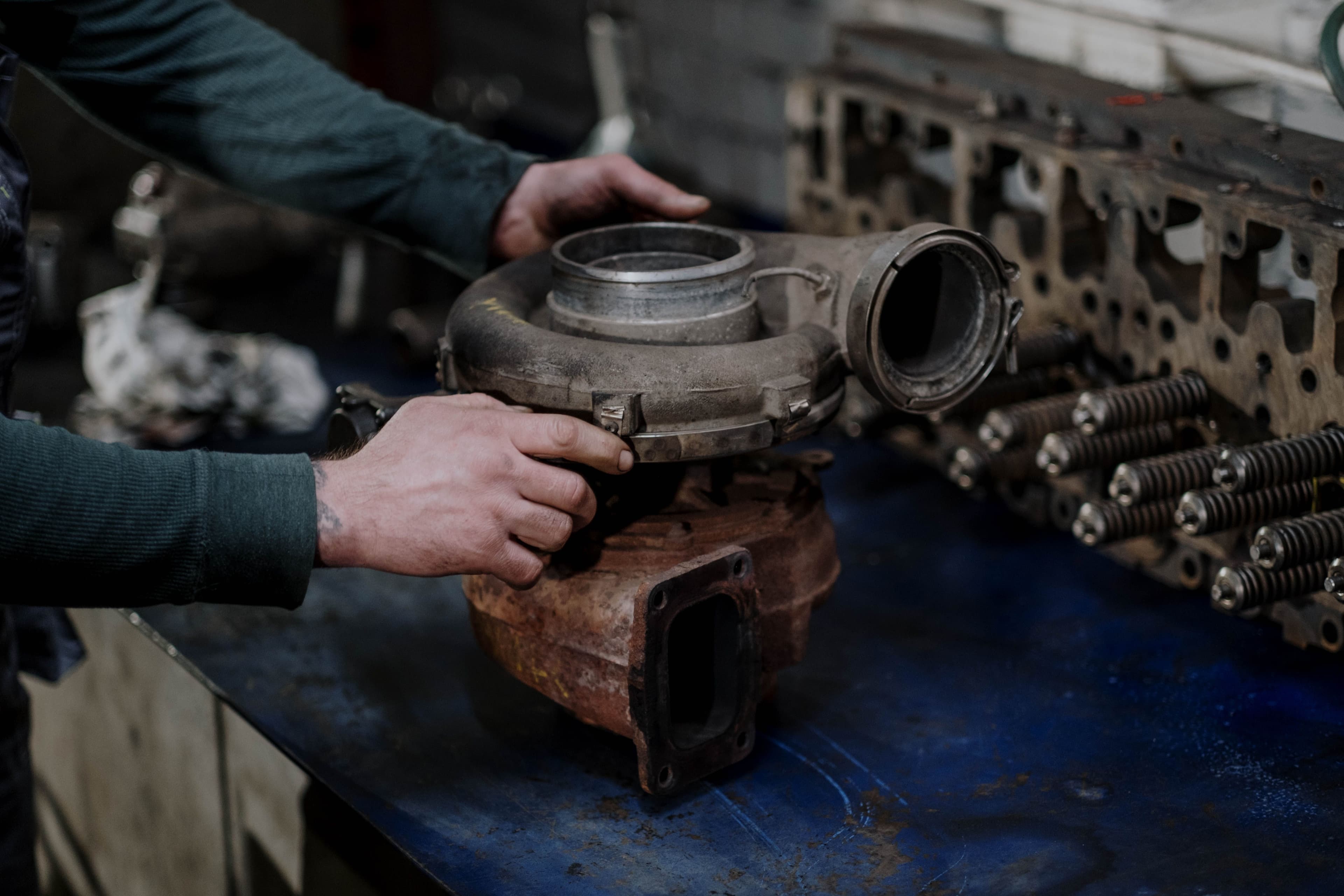 Mechanic holding and inspecting a turbocharger assembly on a workshop bench